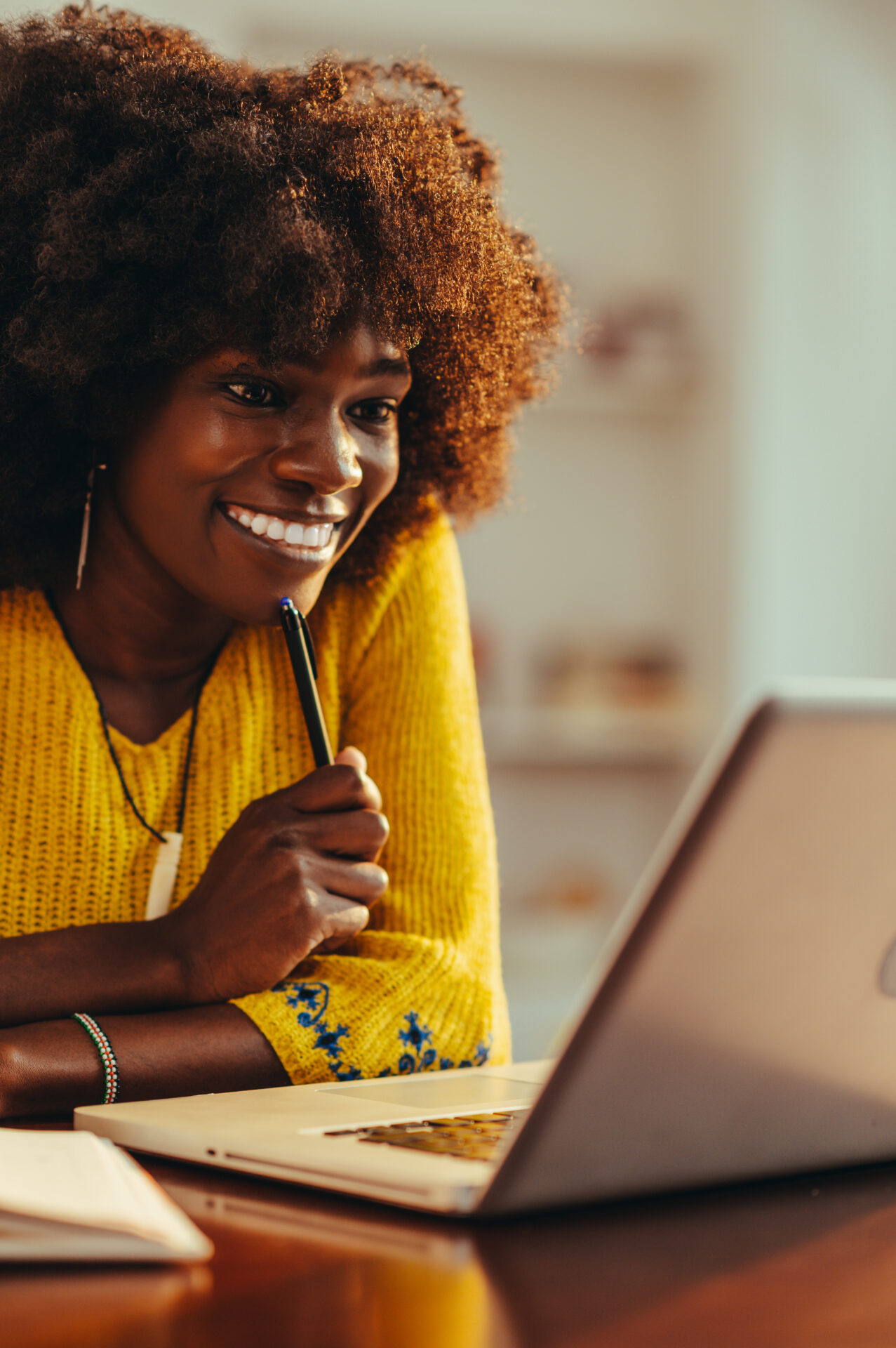 A cheerful african american female student is sitting at home and following an online and lectures on the laptop.